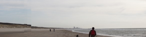 knappe man aan het strand, oprit naar strand, kust, Wassenaarse Slag, hond en man,. balletje gooien, Scheveningen in de verte